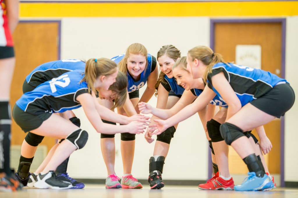 Volleyball team celebrating after coach used a tablet to show the lesson plan